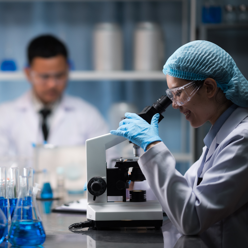 Lab scientist looks through microscope