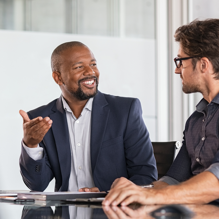 Man smiles to colleague in meeting