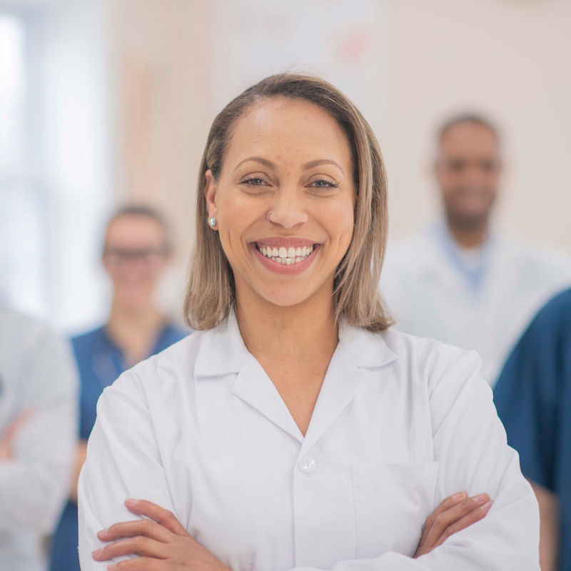 A doctor smiles with her arms crossed